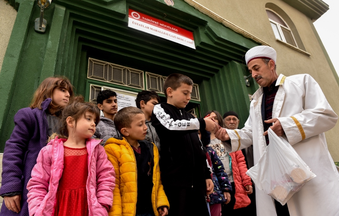 Cami imamı namaza gelen çocuklara çikolata ikram ediyor